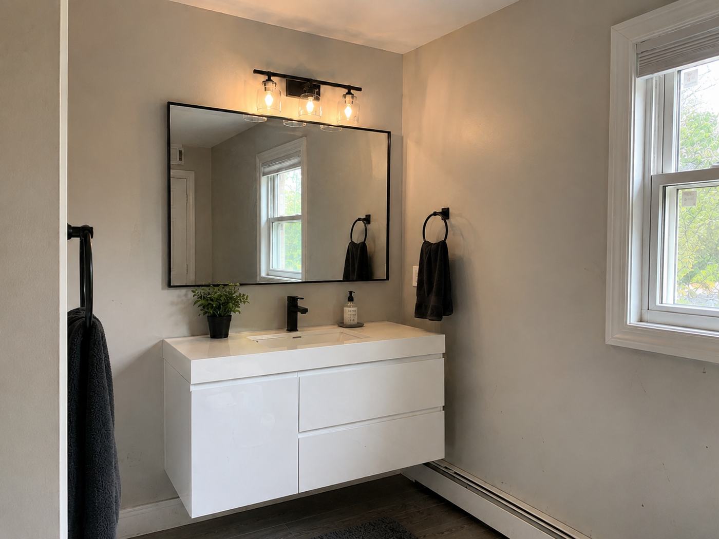 Bathroom with white floating vanity and black fixtures after painting