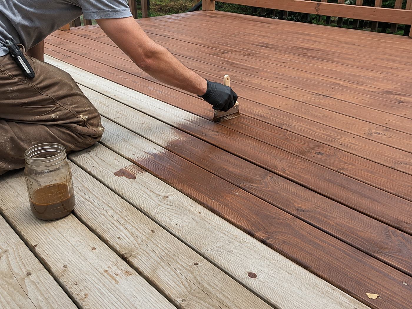 Painter applying stain to a wooden deck