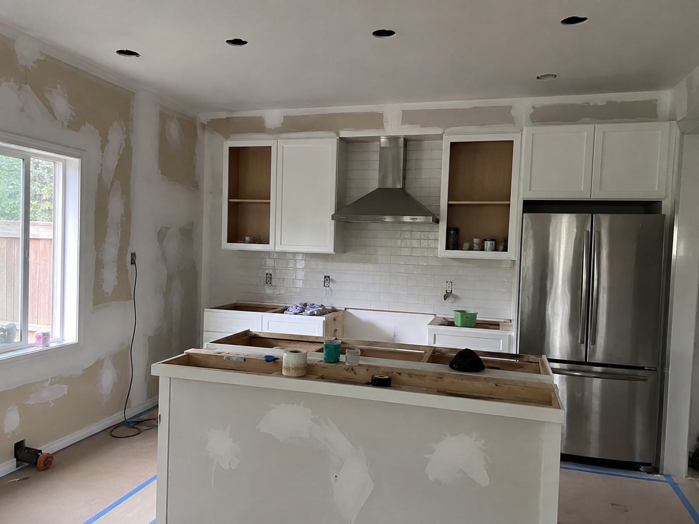 Kitchen renovation in progress with new cabinetry and tile backsplash